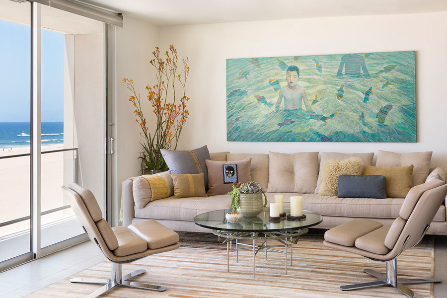 Neutral-colored furniture and walls, and blue-toned artwork reflect the colors found both in the beac