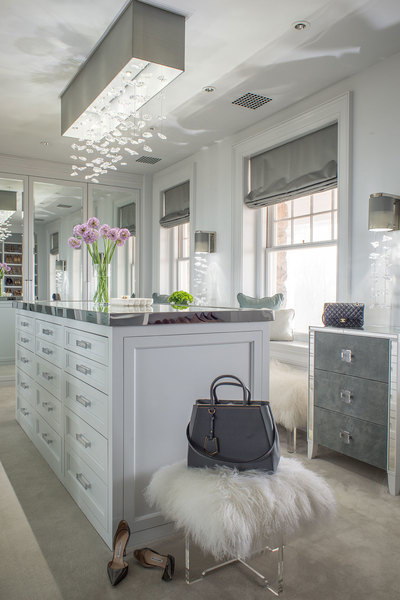 Mirrored finishes and luxe custom lighting, including a modern chandelier, elevate this closet design