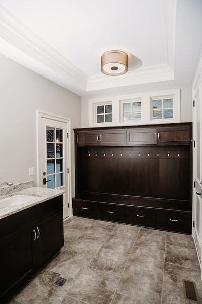 Elements like marble-like tiling and wood cabinetry elevate this mudroom designed by Donna Mondi.